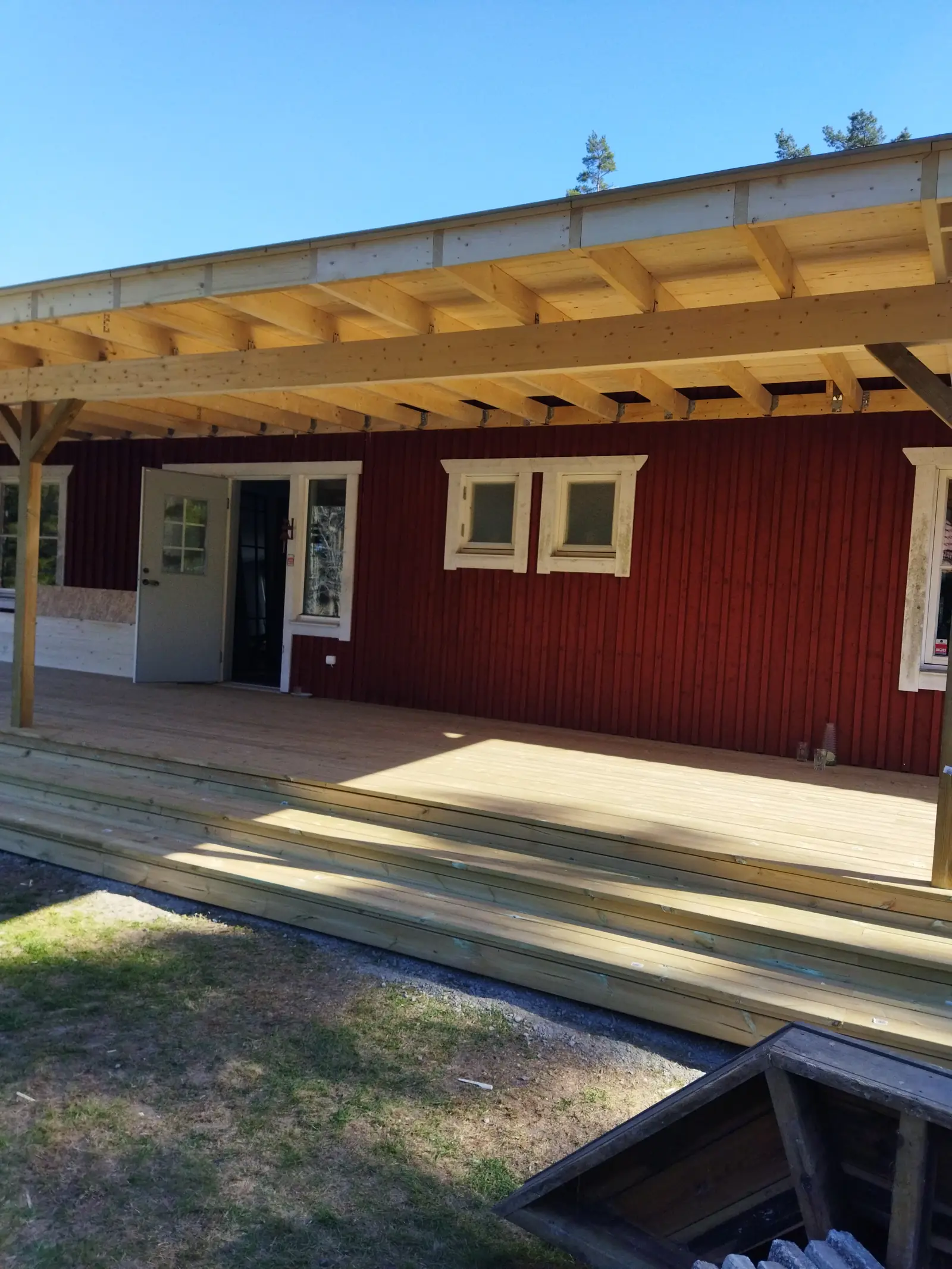 Röd träfasad med flera vitmålade fönster och en glasad ytterdörr